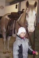 Little girl holding saddled up Curly Horse